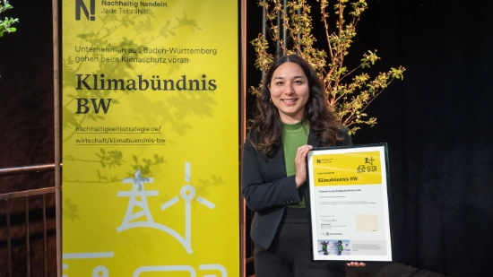A photo of a woman smiling as she holds up a certificate marking the group’s membership.