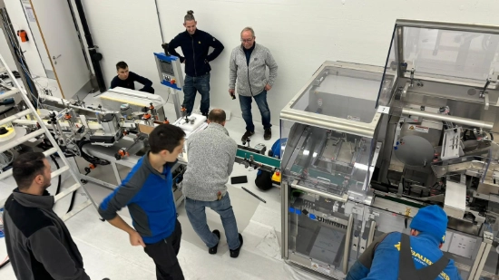 Several people connecting the labeling machine to the cartoning machine