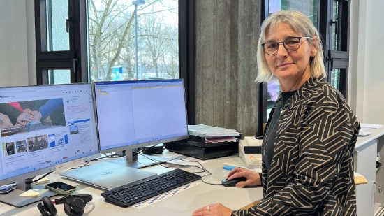 Ingrid Schick working at a desk with two monitors in an office.