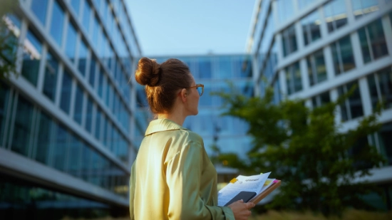 Person holding documents in front of a modern office building