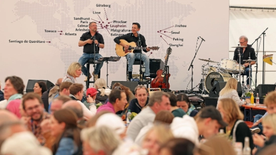 Zwei Musiker performen auf einer Bühne vor sitzendem Publikum.