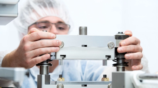 Employees wearing protective clothing assembling format parts in a hygienically controlled production environment