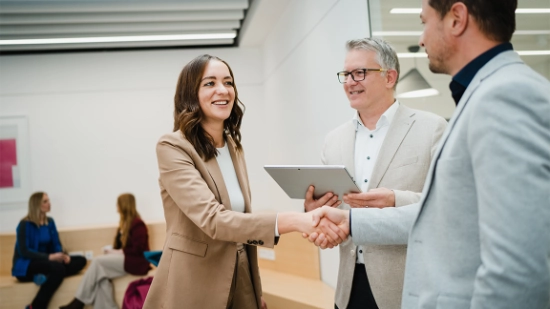 Greeting scene between several people in a modern office corridor.