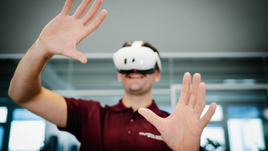Person wearing a VR headset with raised hands interacting in a digital environment.