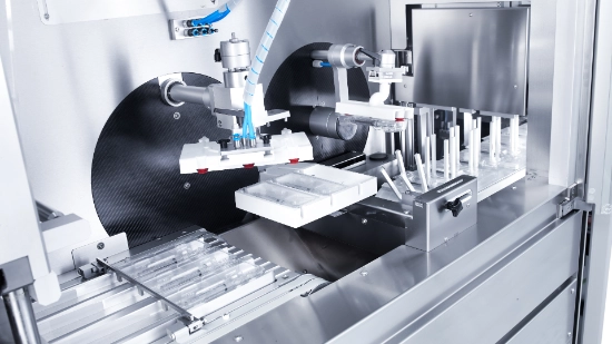 Primer plano de una máquina de blísteres Uhlmann para parenterales, con sistema de transferencia a la estuchadora