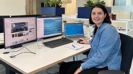 Christiane Werz sitting at her desk with two monitors and a laptop