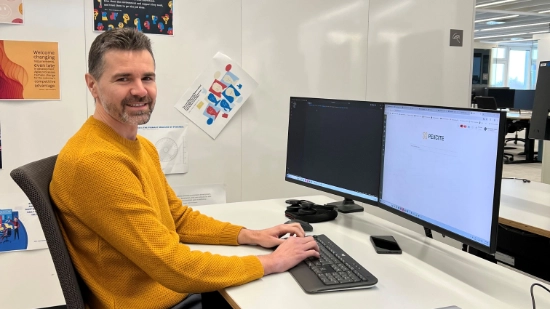 Ibrahim working at a desk on a computer with two monitors
