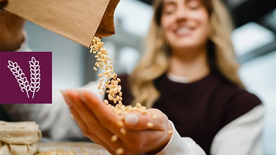 A female person ist holding grains while additional grains are poured from a paper bag. An icon on the image shows wheat, symbolizing agricultural products.