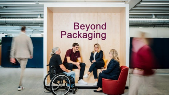 Group of people sitting in a modern office lounge with the words “Beyond Packaging” in the background.