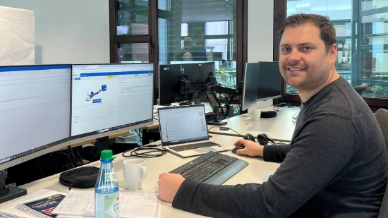 Christoph Werz sitting at his desk in front of two monitors and a laptop.