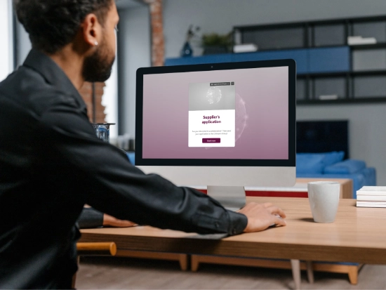 A man sitting in front of a computer screen showing a form to apply as a supplier.