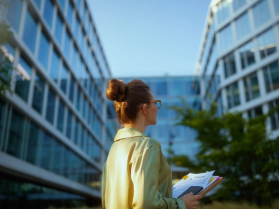 Person holding documents in front of a modern office building