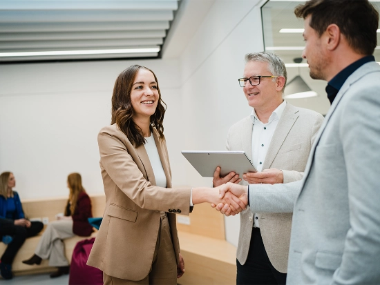 Greeting scene between several people in a modern office.