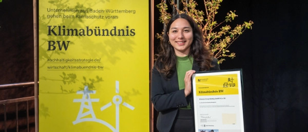 A photo of a woman smiling as she holds up a certificate marking the group’s membership.