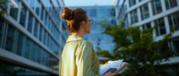 Person holding documents in front of a modern office building