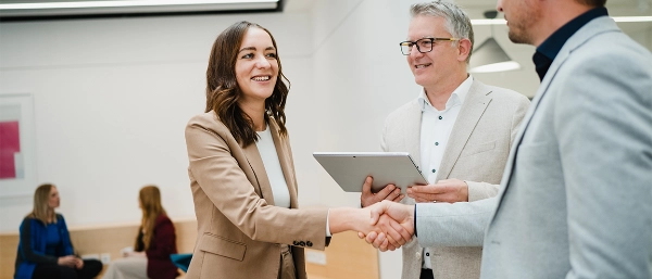 Greeting scene between several people in a modern office corridor.