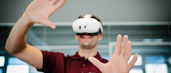 Person wearing a VR headset with raised hands interacting in a digital environment.