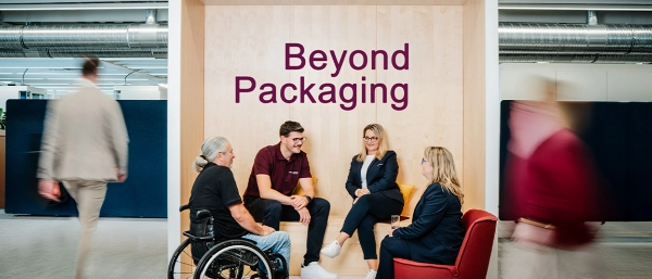 Group of people sitting in a modern office lounge with the words “Beyond Packaging” in the background.